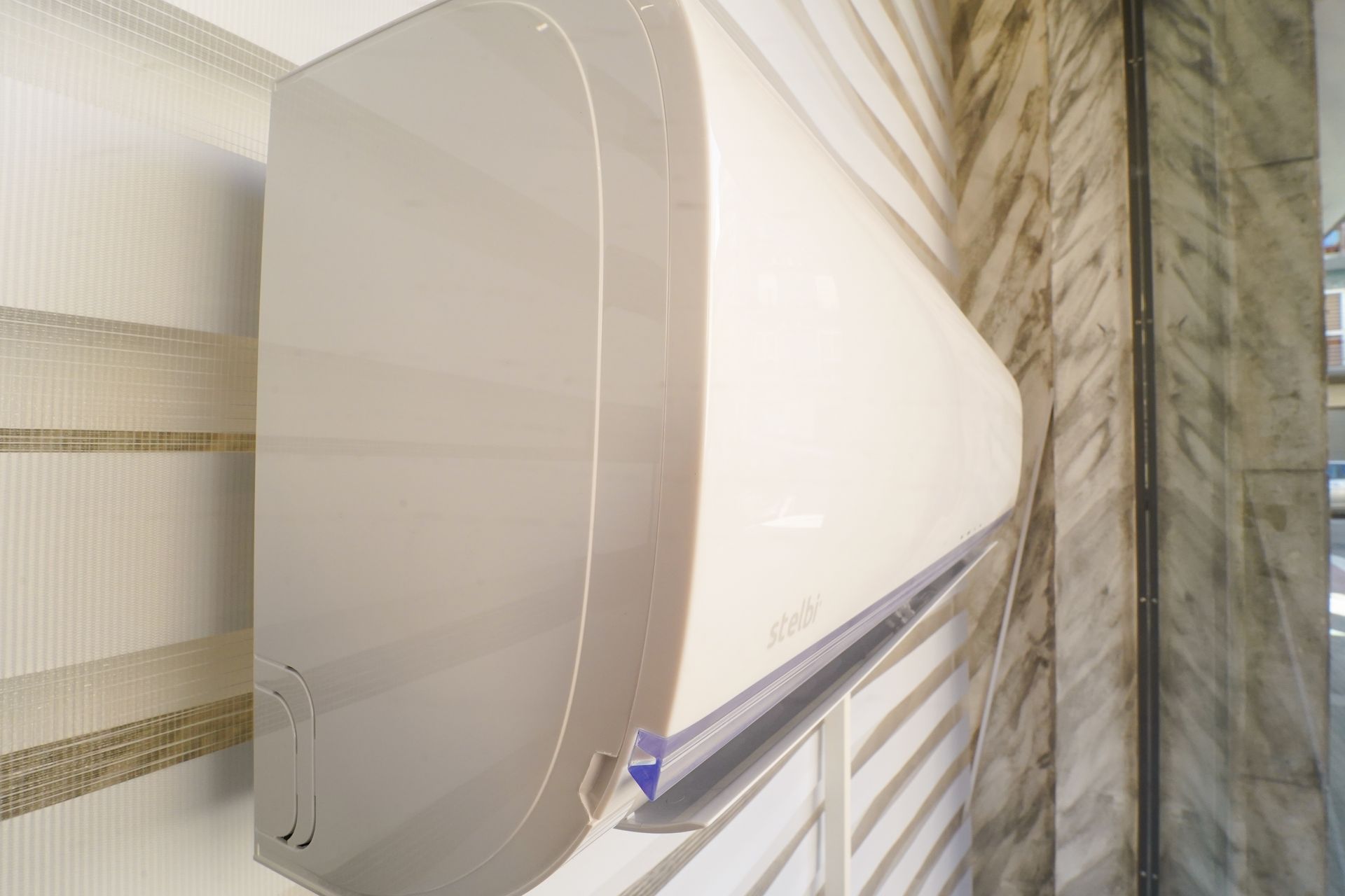 Condizionatore d'aria bianco montato su una parete testurizzata beige e grigia.