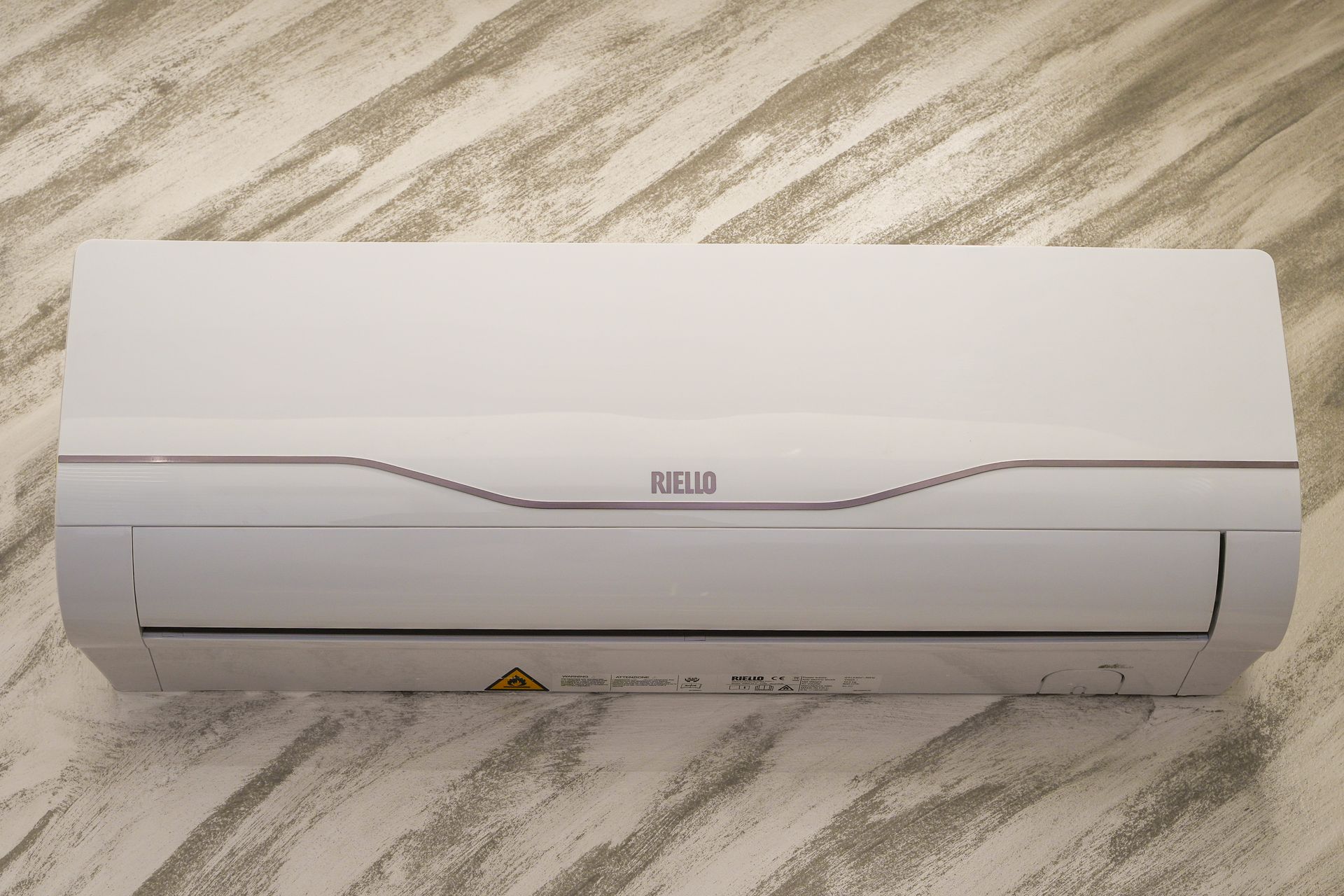 Condizionatore d'aria bianco montato su una parete chiara e strutturata.