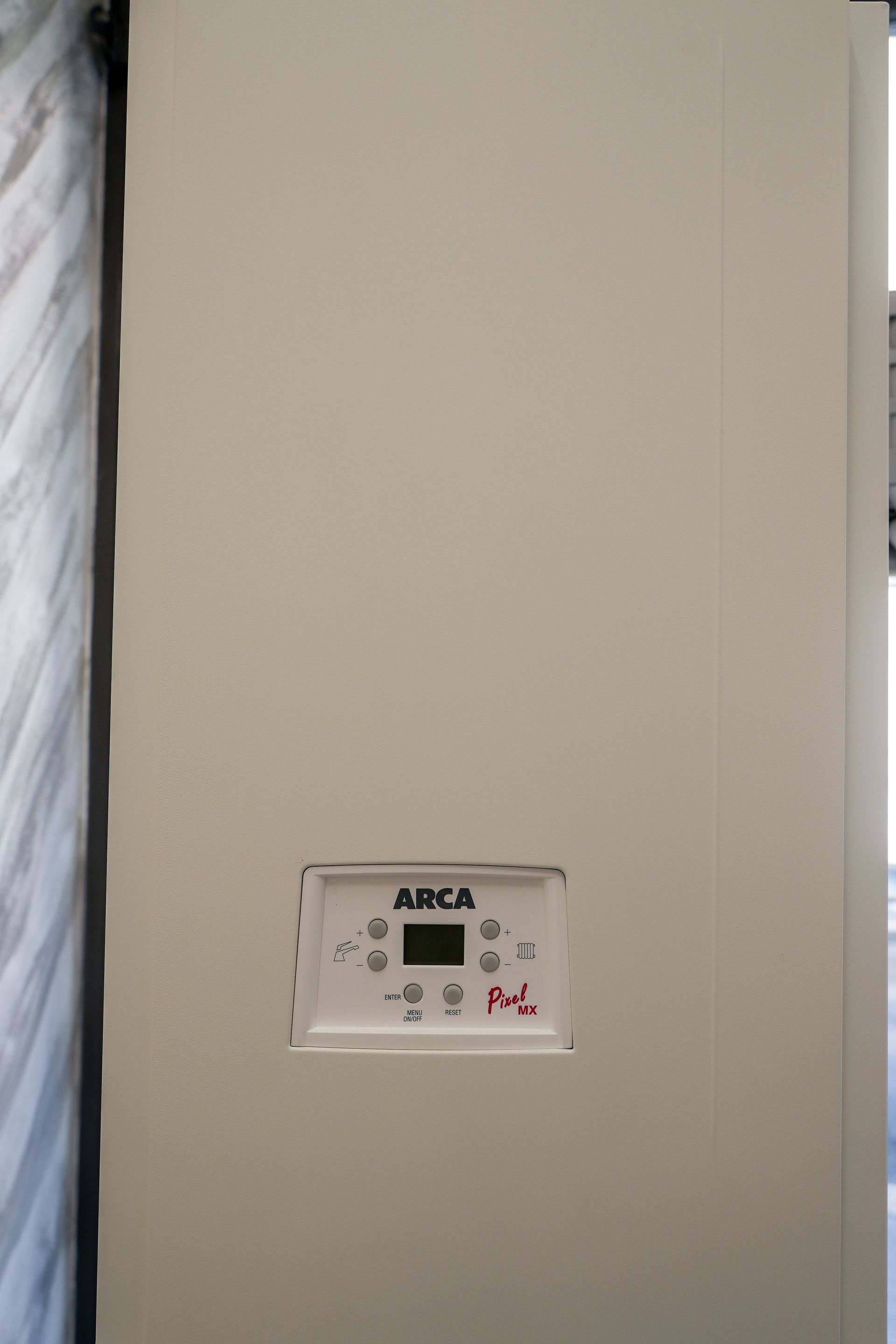 Una caldaia ARCA beige con un pannello di controllo che mostra un piccolo schermo digitale e dei pulsanti.