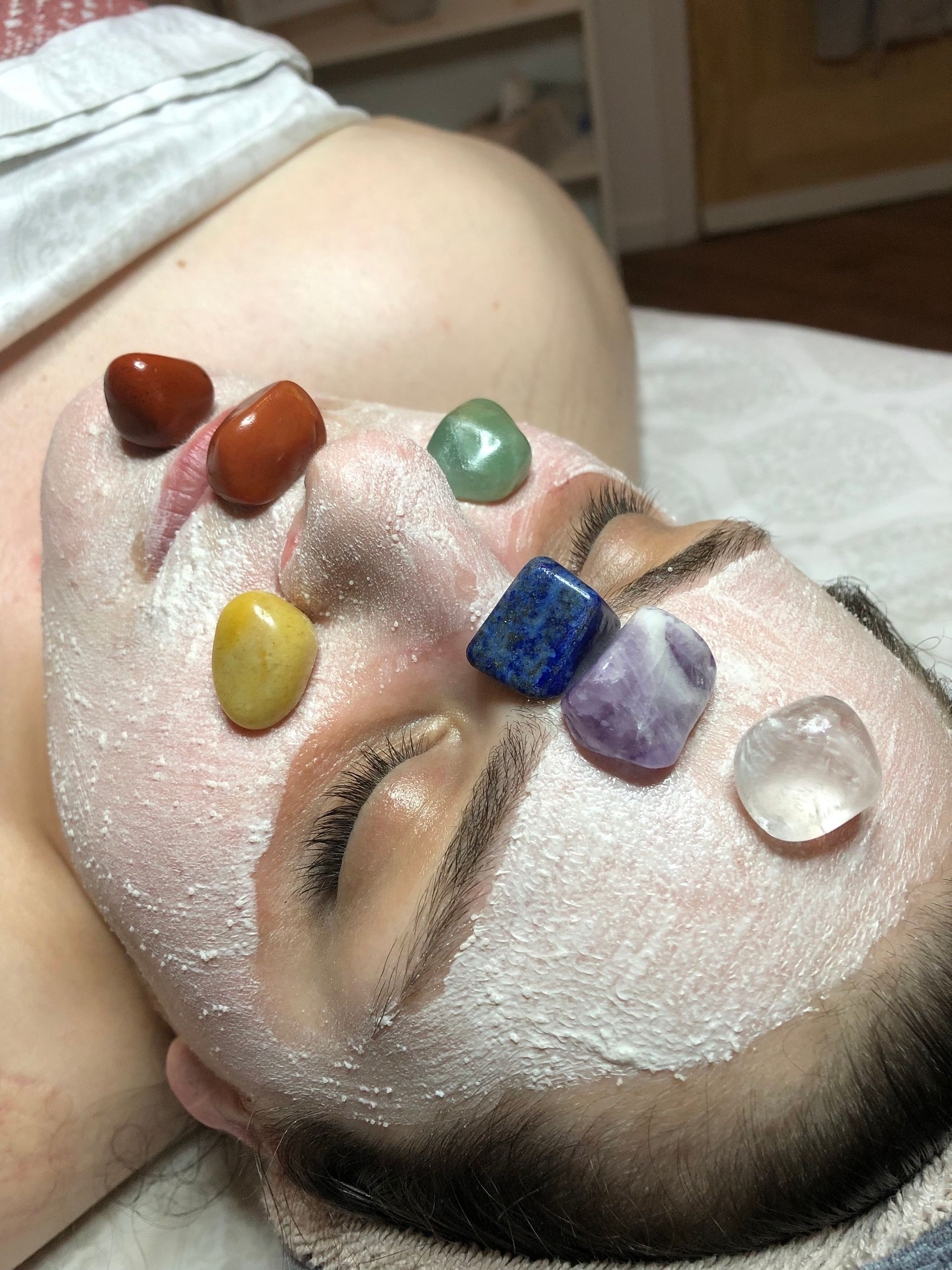 A woman is laying on a bed with a facial mask on her face.