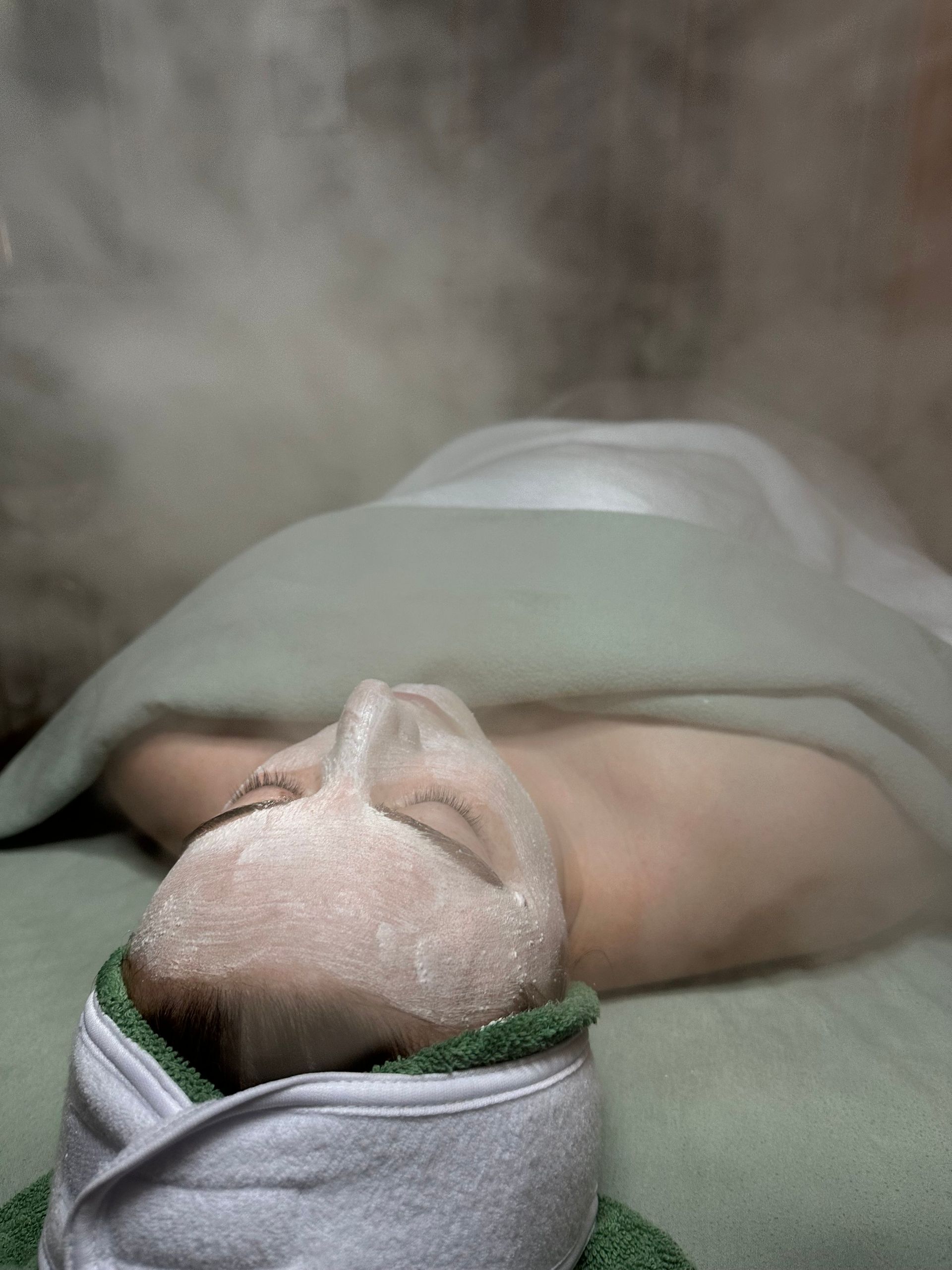 A woman is laying on a bed with a mask on her face.