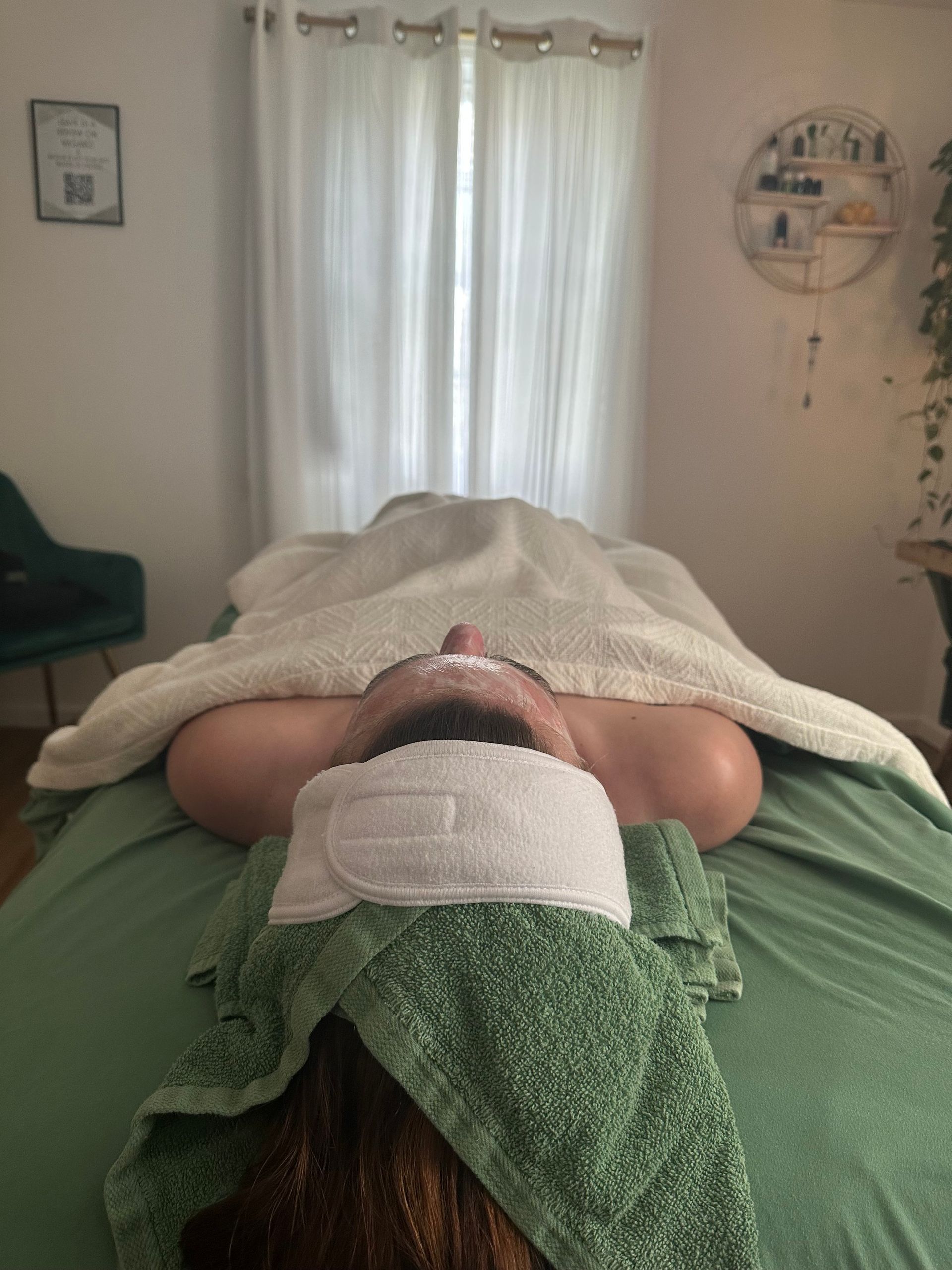 A woman is laying on a massage table with a towel on her head.