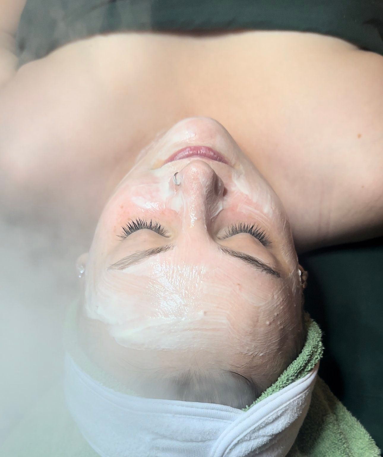 A woman is laying on her back with her eyes closed and a mask on her face.