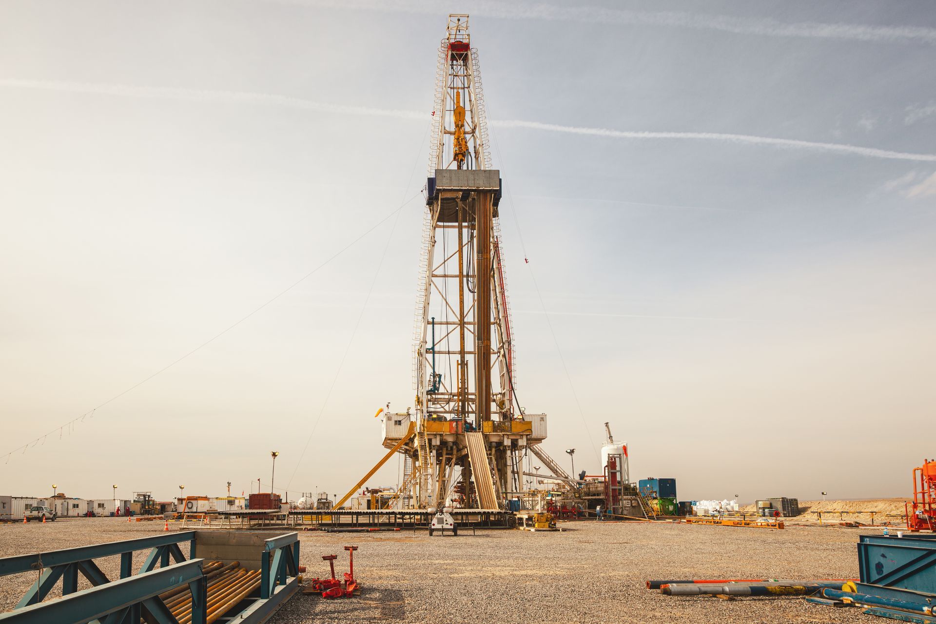 Oil drilling rig on a dusty site under a bright sky