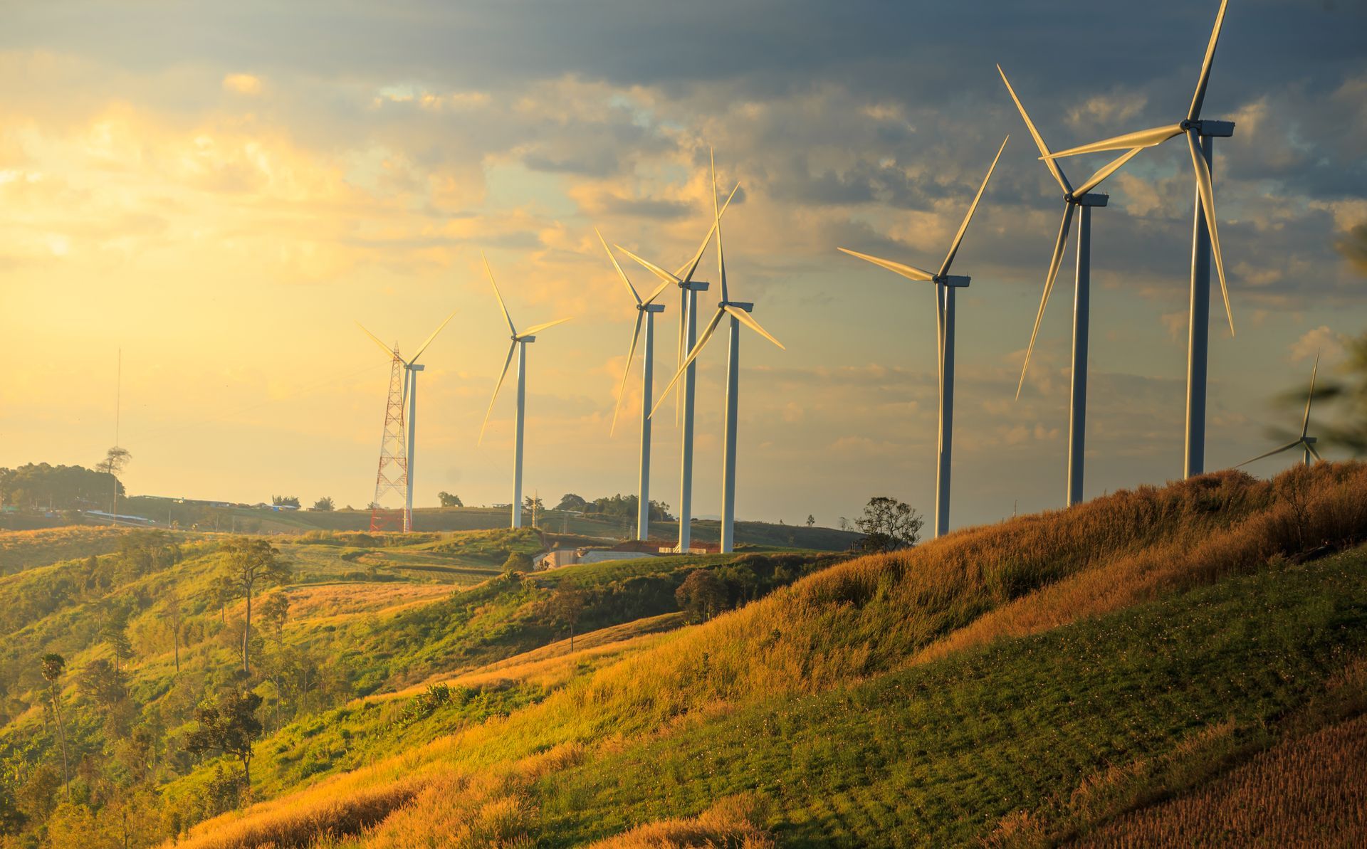 Wind turbines on a hillside against a cloudy sunset