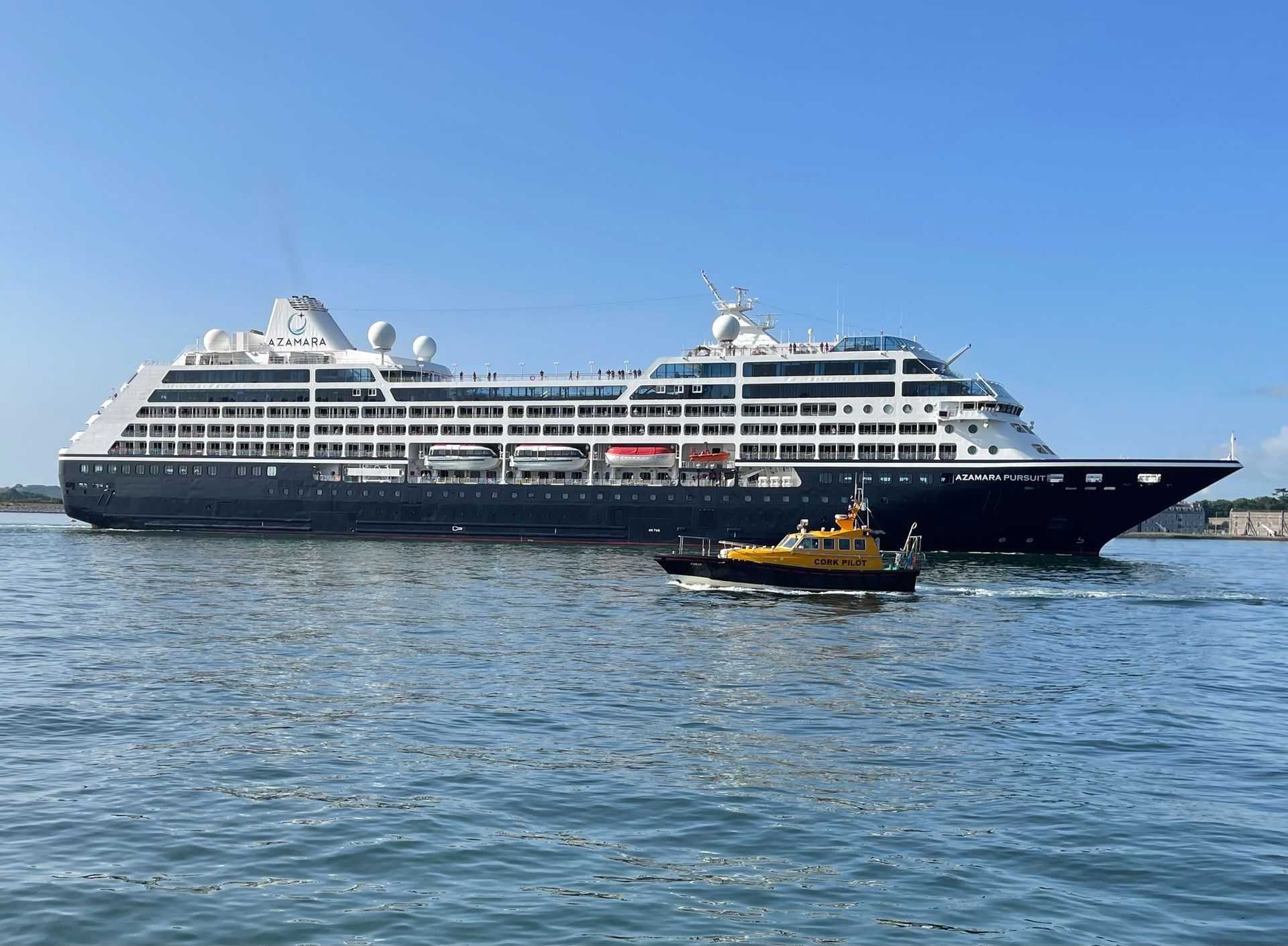 a large cruise ship is docked in the water next to a small boat .