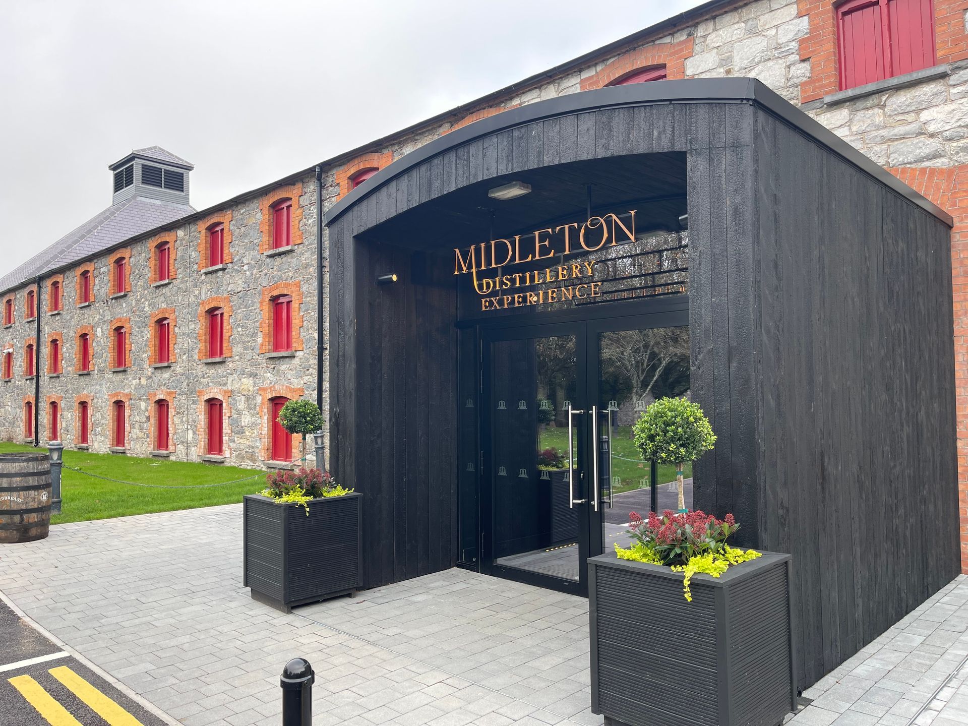 A large stone building with a black entrance and planters in front of it.