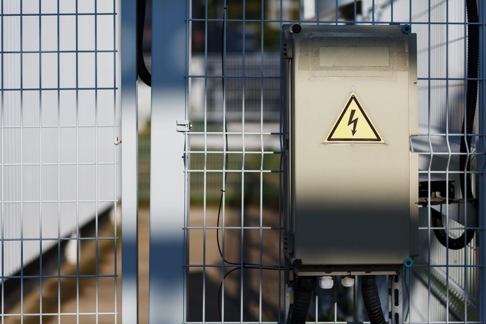 Metal Electrical Box With High Voltage Warning Symbol on a Fenced Enclosure — FAW Electrical in Callala Beach, NSW