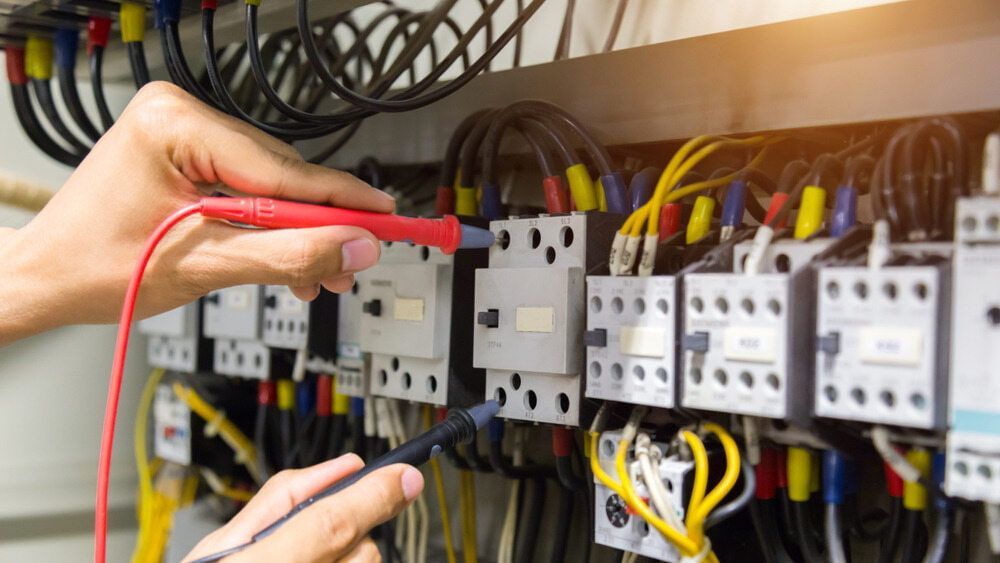 Electrician Using a Multimeter to Test Wiring in a Control Panel — FAW Electrical in Southern Highlands, NSW