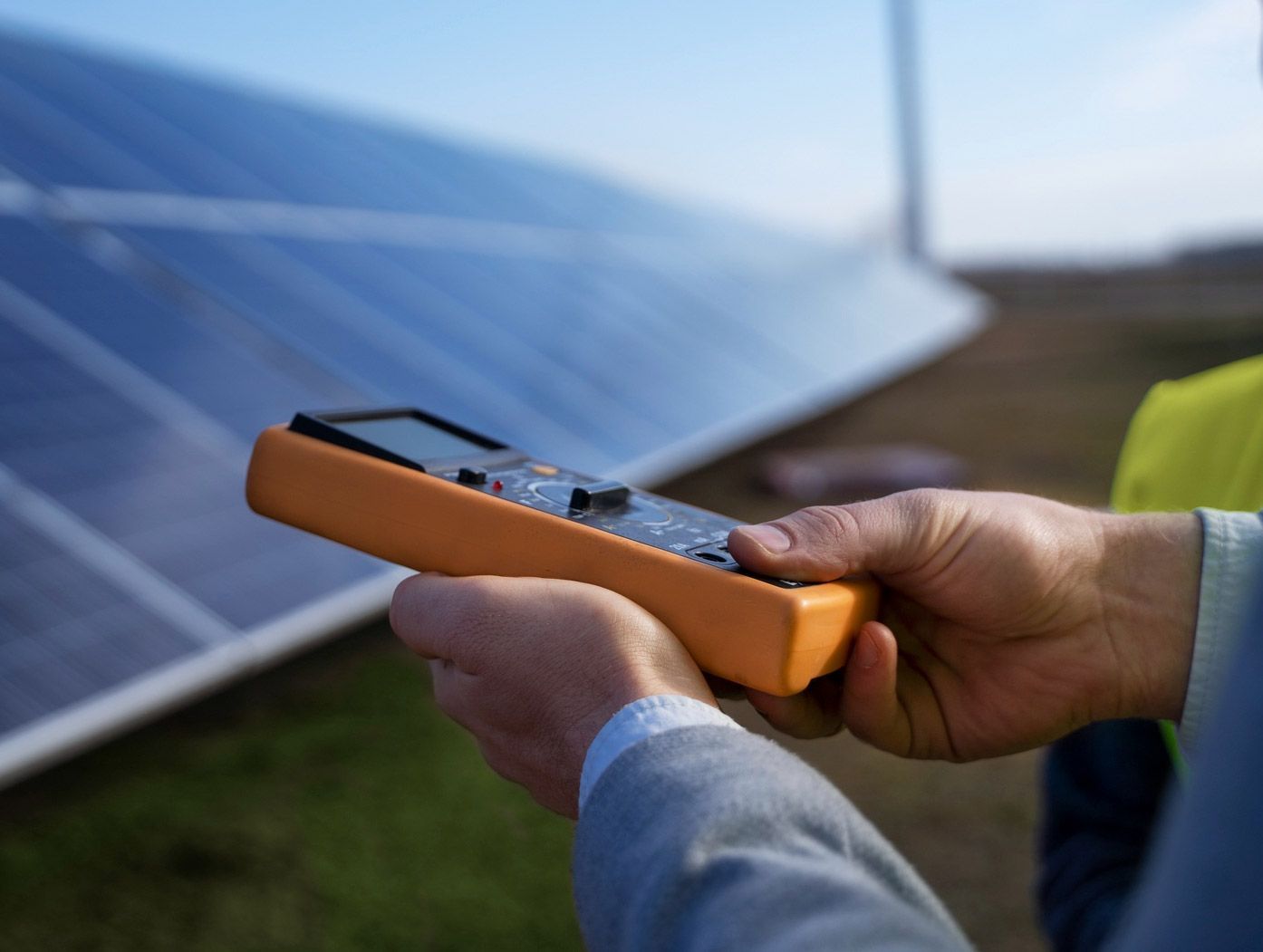 Person Holding an Orange Multimeter, Testing Solar Panels Outdoors — FAW Electrical in Callala Beach, NSW