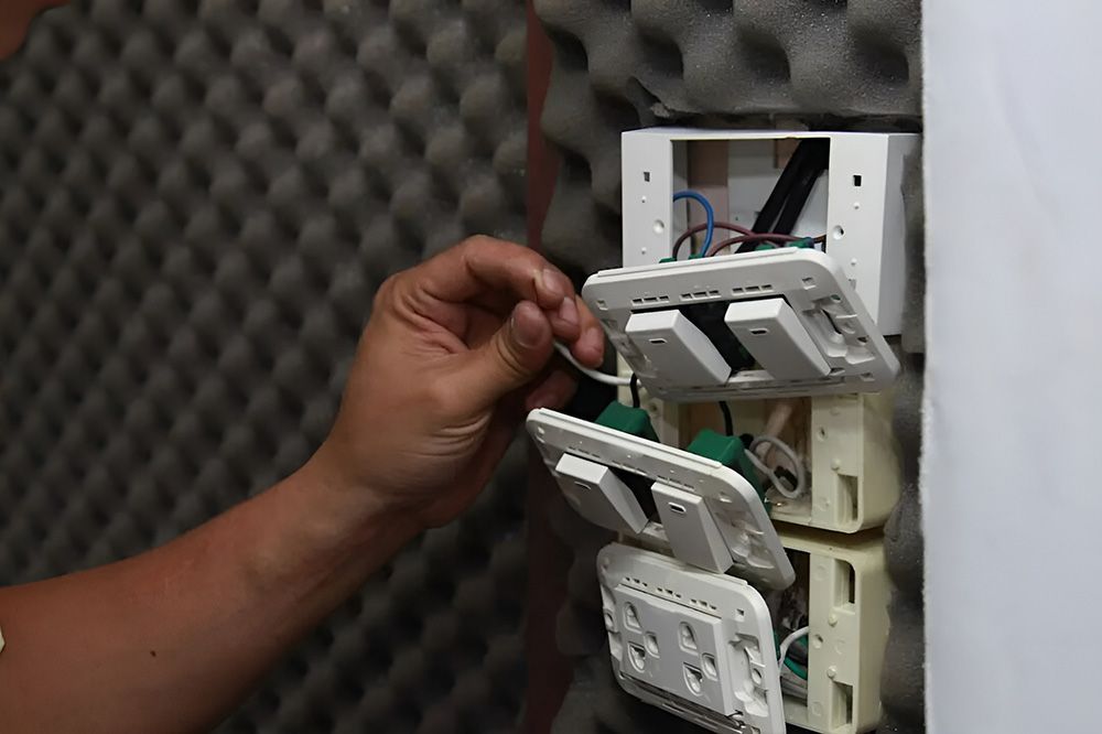 Person Wiring Electrical Outlets On A Wall — FAW Electrical in Nowra Hill, NSW