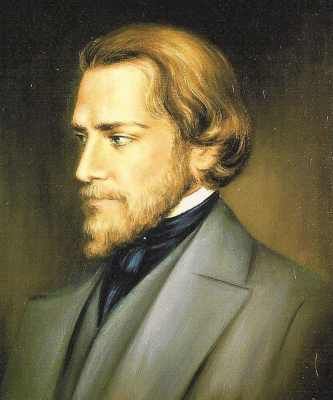 Portrait of a man with blond hair and beard, in a grey suit.