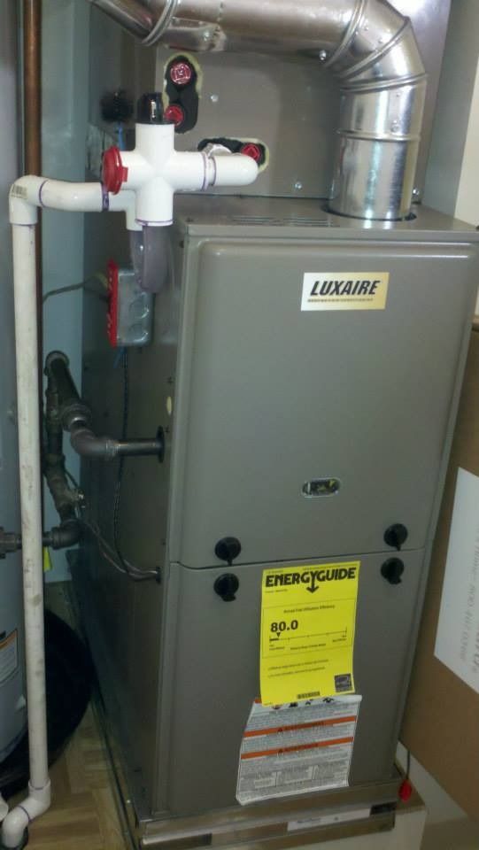 Gray Lennoxaire furnace with white PVC pipes and silver exhaust ducting in a utility room.