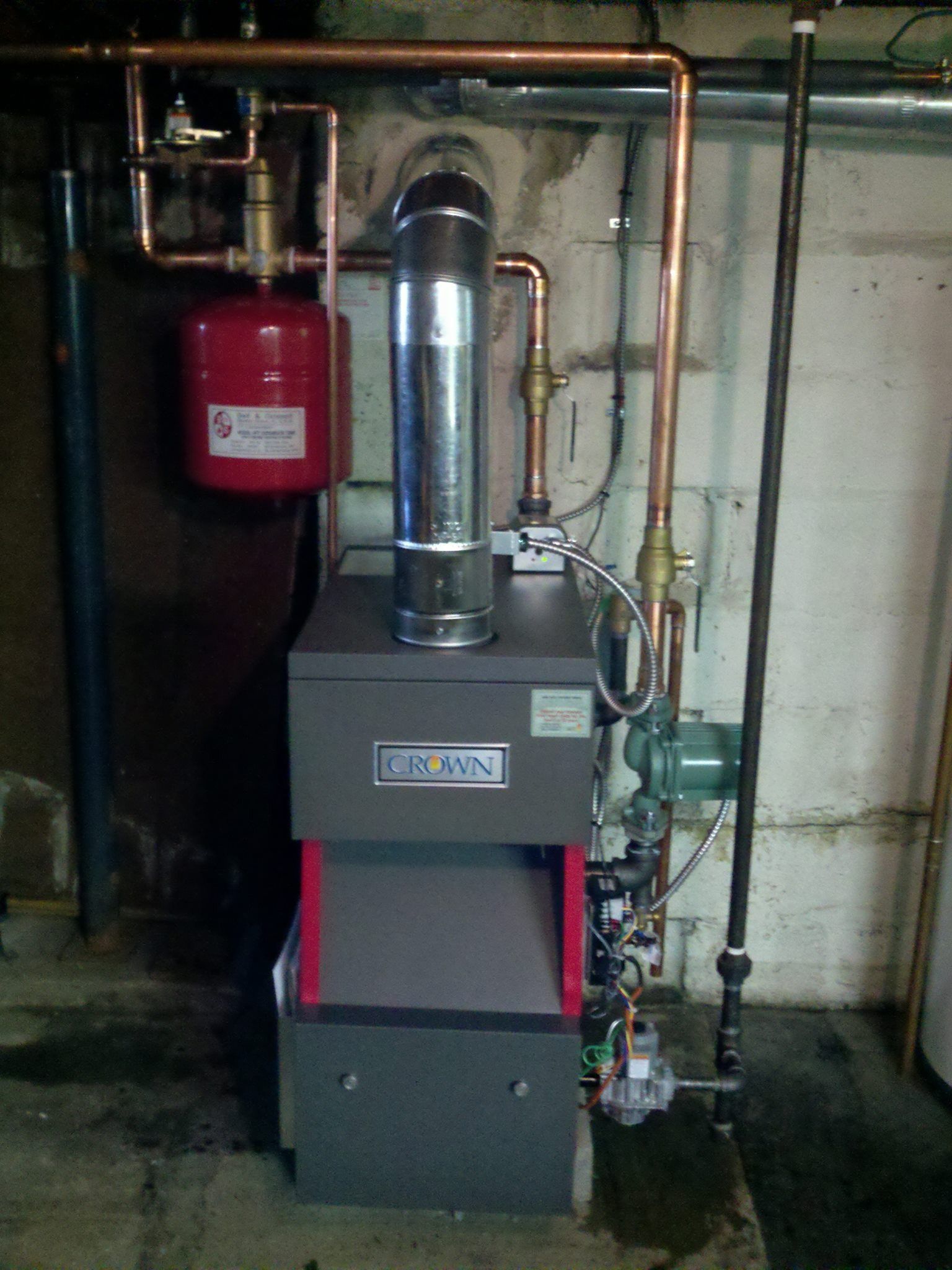 A gray Burnham oil-fired boiler with red accents and copper piping in a basement setting.