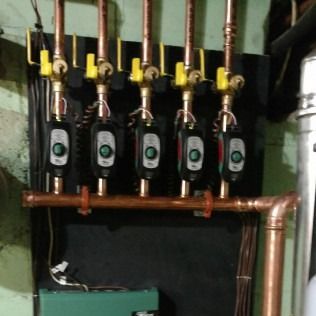 Copper pipes with valves and pumps attached to a dark surface.