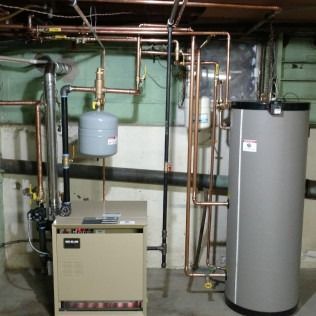 Heating system with copper pipes, a water tank, and a control panel in a basement setting.