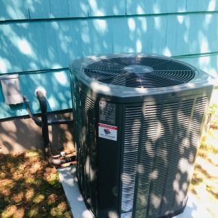 Air conditioning unit outside a blue-painted building.