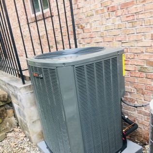 Gray air conditioning unit next to a brick building.