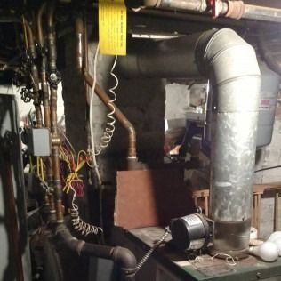 Basement with pipes, furnace, and vent. Electrical wiring and yellow tag are visible.