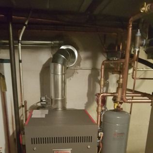 A gas-fired boiler with vent pipe, copper piping, and an expansion tank in a basement.