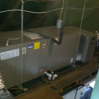 HVAC unit in an attic, with electrical wiring. A person in blue is near the unit.