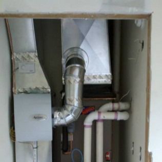 HVAC system components, including ductwork, furnace, and pipes, are installed in a wall.