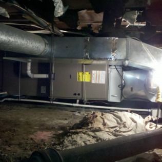 HVAC unit in crawlspace, silver ductwork, with insulation and debris on the ground.