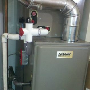 Luxaire furnace with white PVC piping, gray metal cabinet, and metal vent.