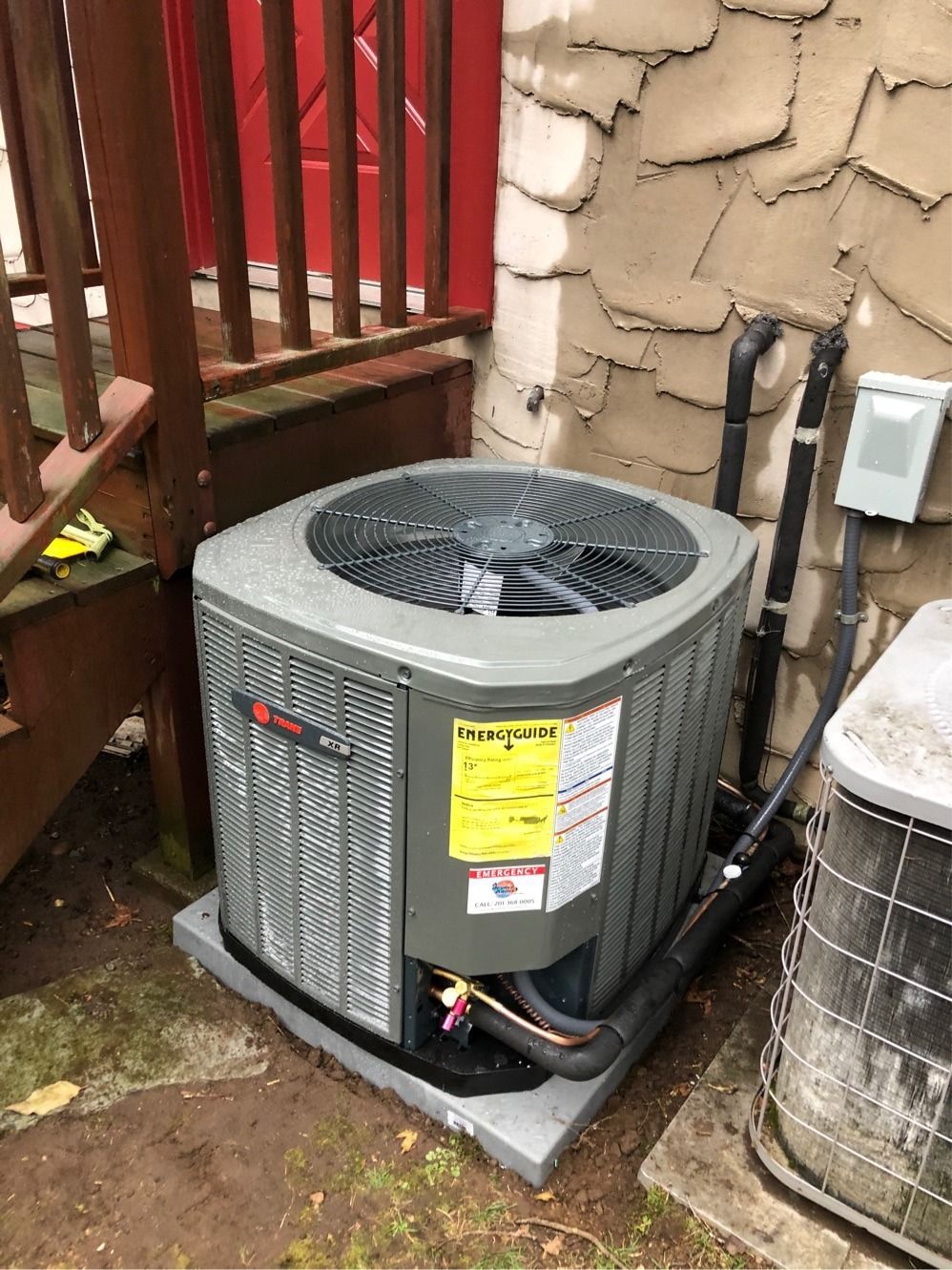 An outdoor air conditioning unit with a fan and a yellow energy efficiency sticker.
