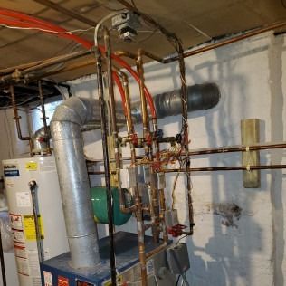 Basement with boiler, water heater, and complex copper pipe system.