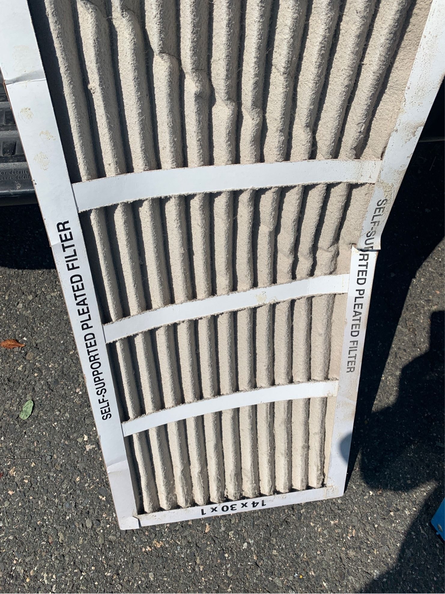 Dirty air filter, pleated design, covered in dust and debris, rectangular shape.