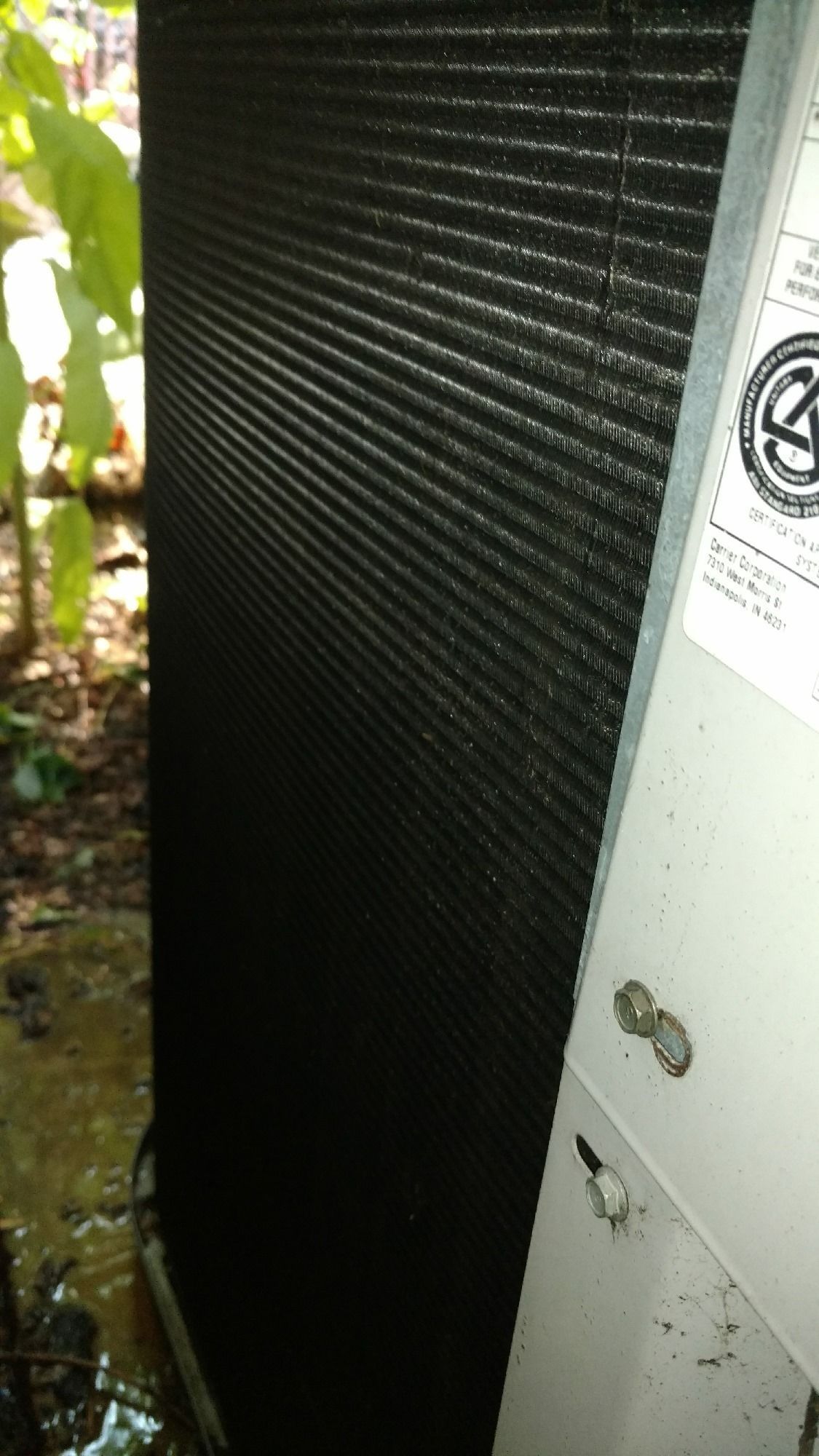 Air conditioner unit with black fins, outdoors.