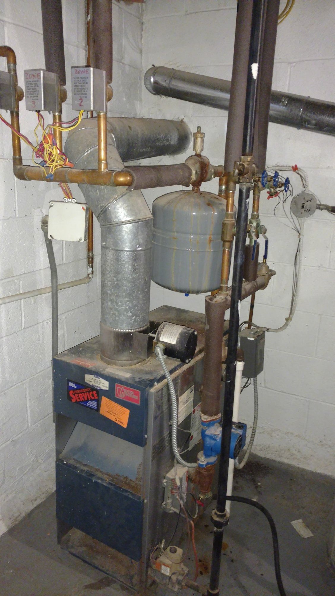 An old blue furnace with pipes and vents in a basement.
