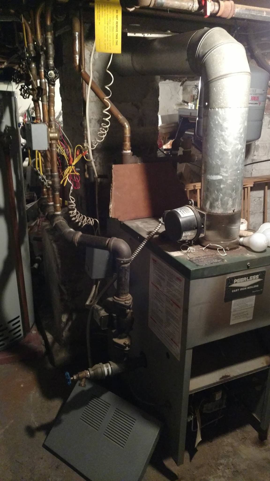 Basement with heating system, pipes, and flue. Gray furnace, copper pipes, and a vent.