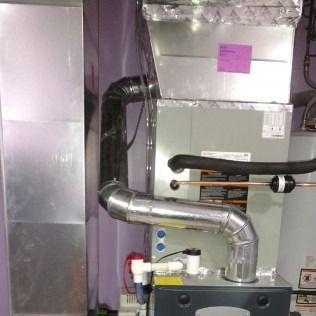 A gray HVAC unit with ductwork in a room with purple walls.