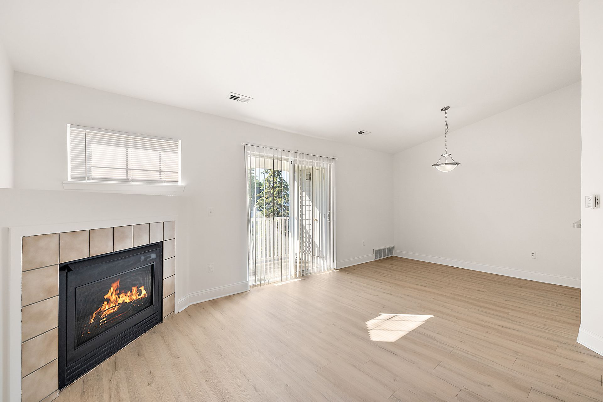 An empty living room with a fireplace and sliding glass doors.