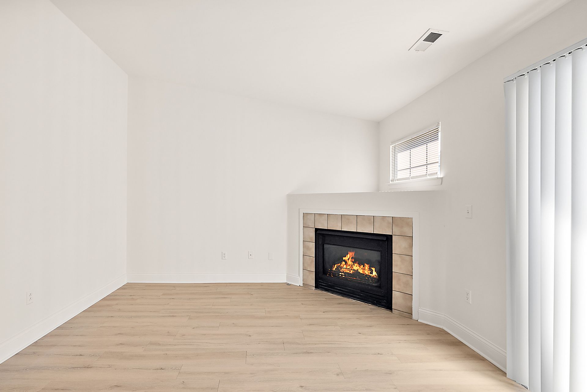An empty living room with a fireplace and a window.