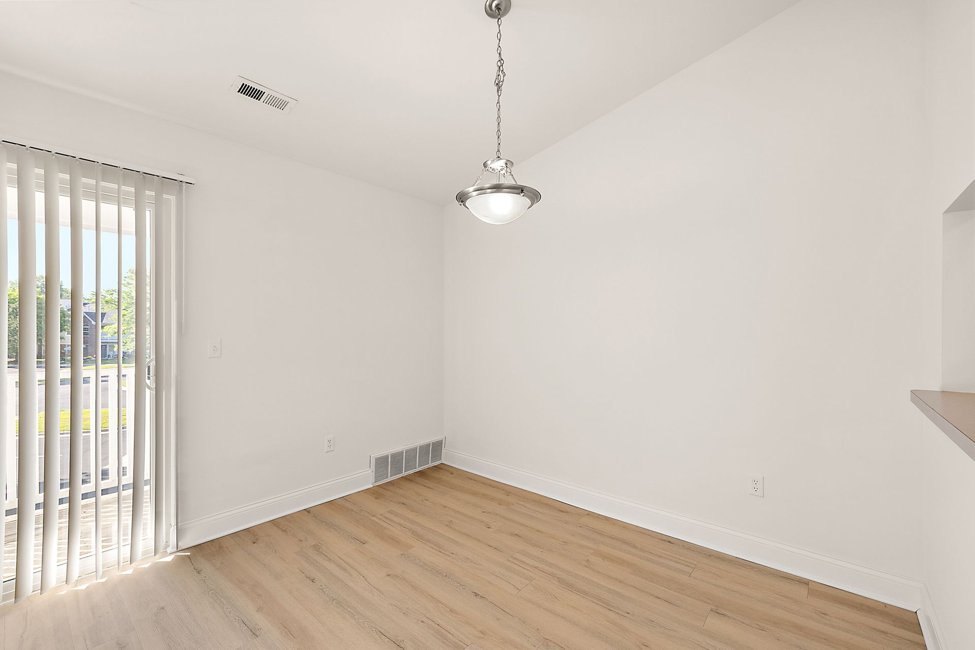 An empty dining room with hardwood floors and a ceiling fan.