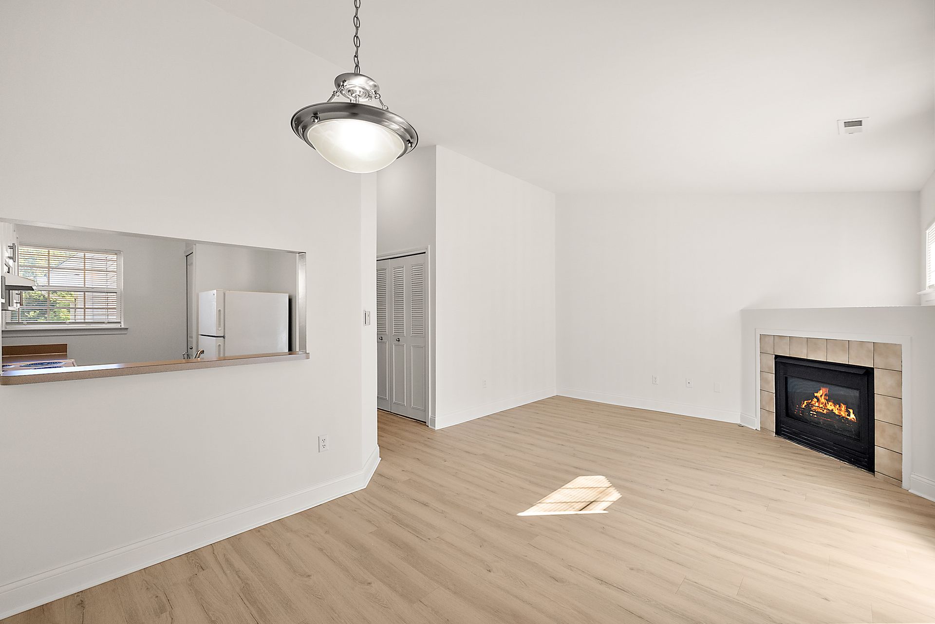 An empty living room with hardwood floors and a fireplace.
