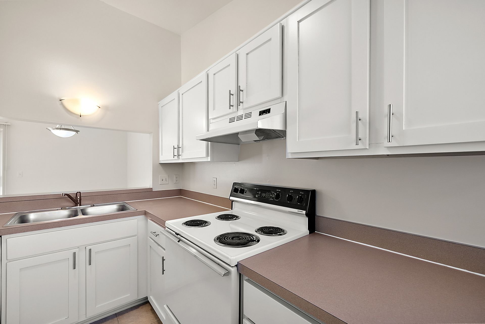 A kitchen with white cabinets , a stove and a sink