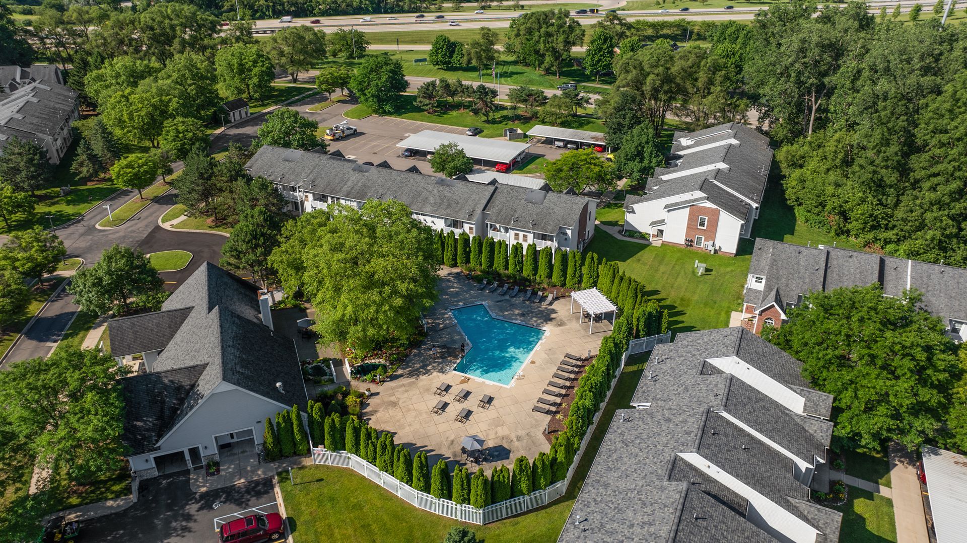 An aerial view of a residential area with a swimming pool surrounded by trees.
