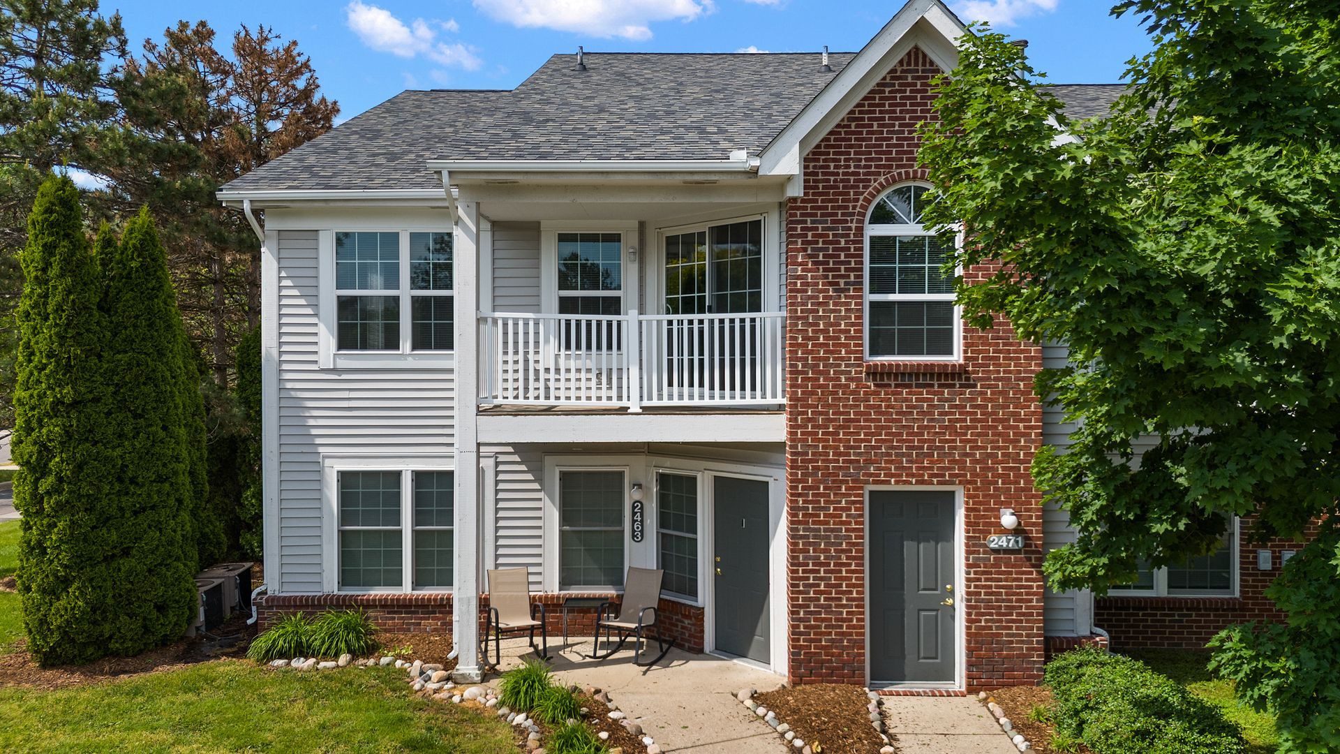 A large brick house with a white siding and a balcony.