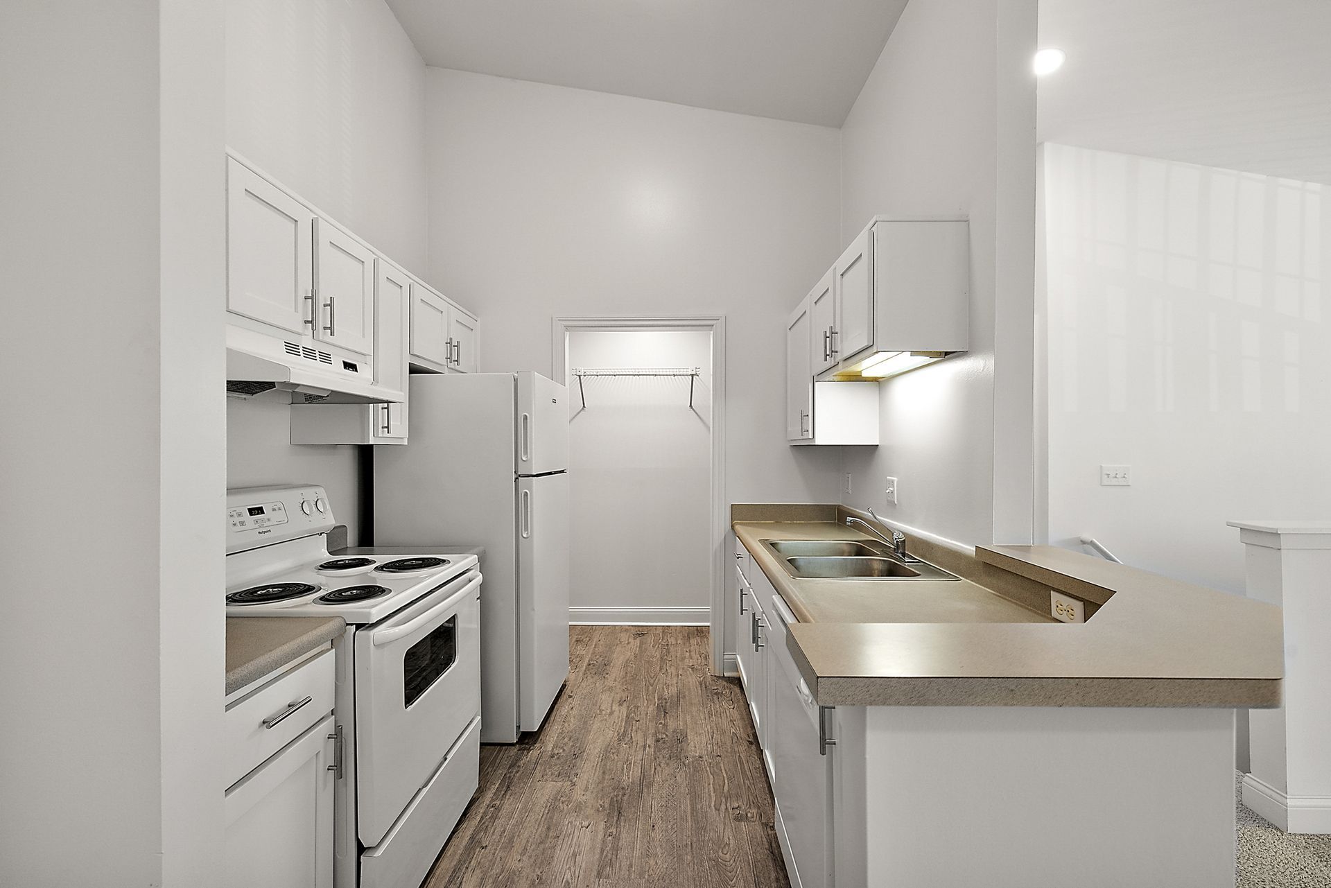 A kitchen with white cabinets , a stove , a refrigerator , and a sink.