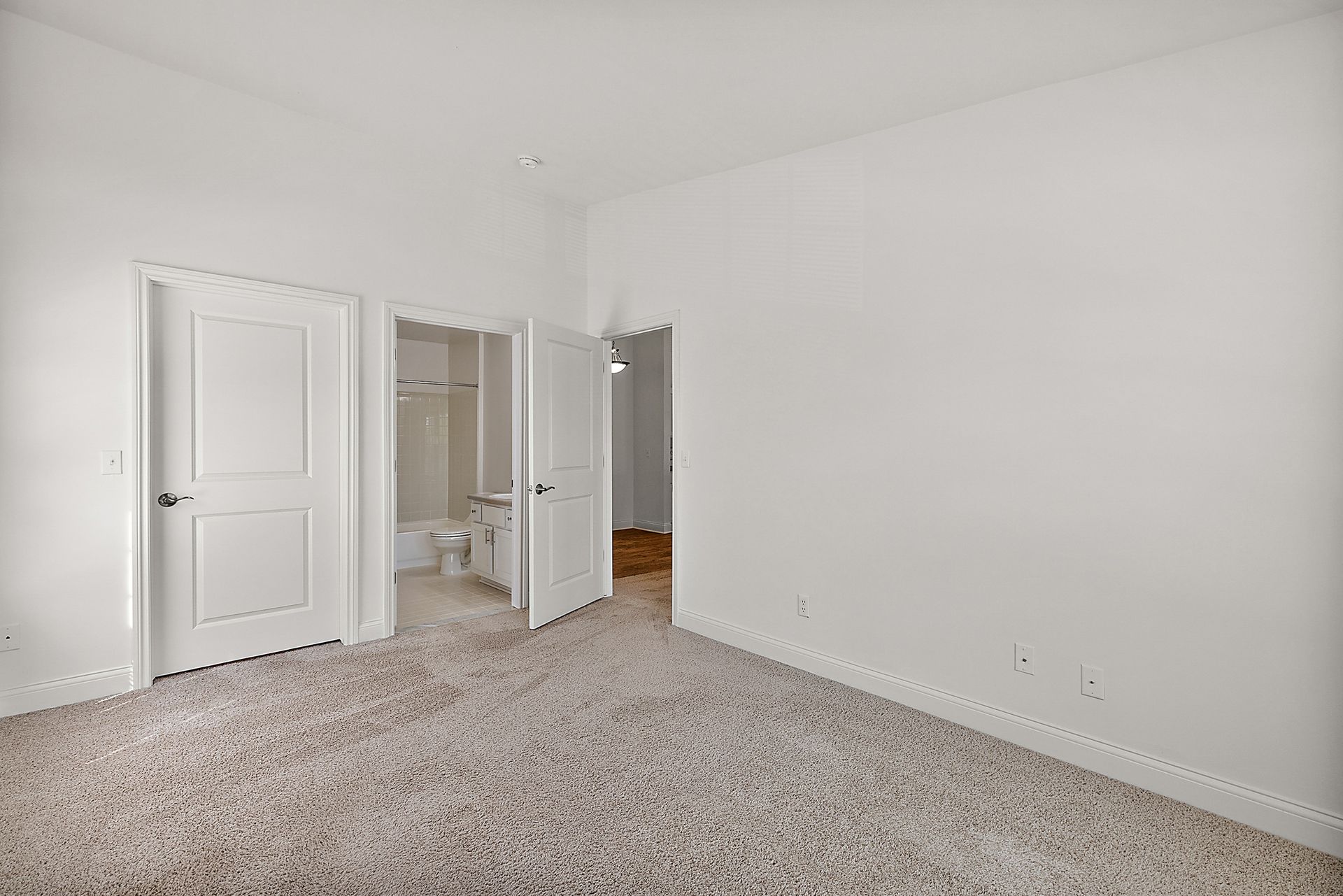 An empty bedroom with a carpeted floor and white walls.