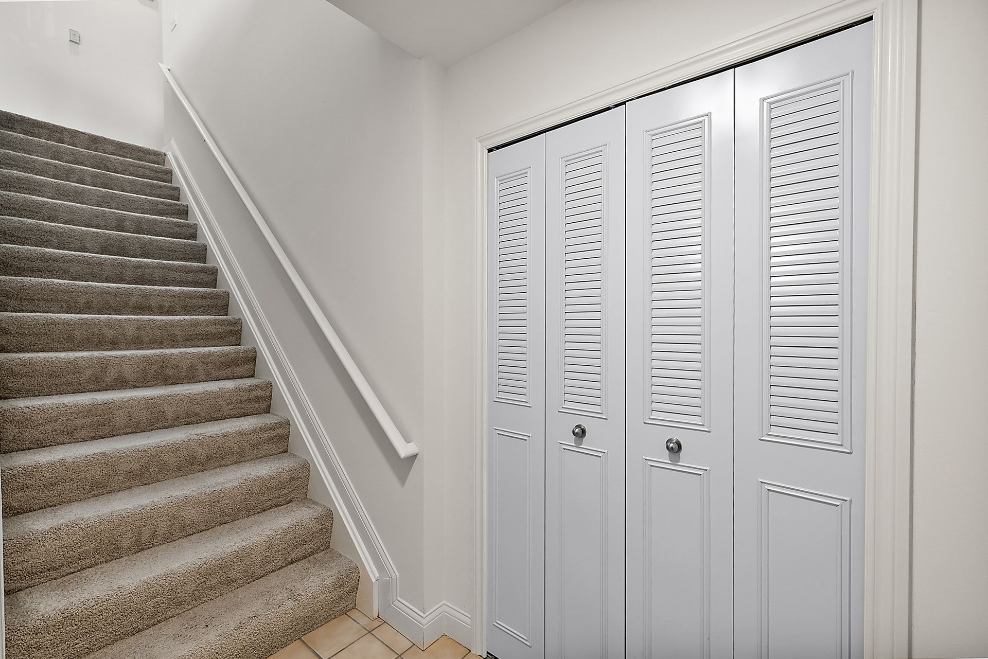 A staircase leading up to a closet with a white door.