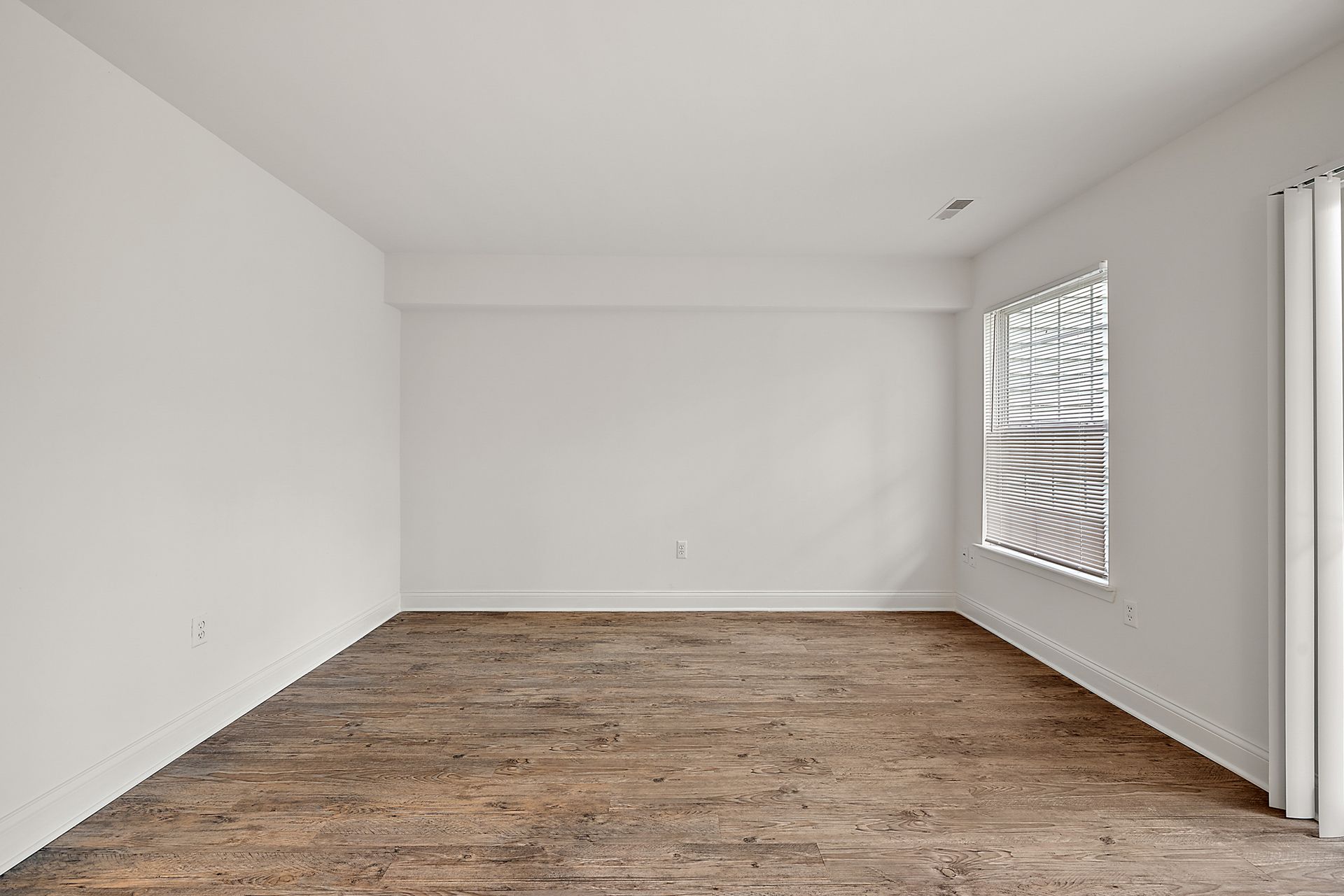 An empty room with wooden floors and white walls.