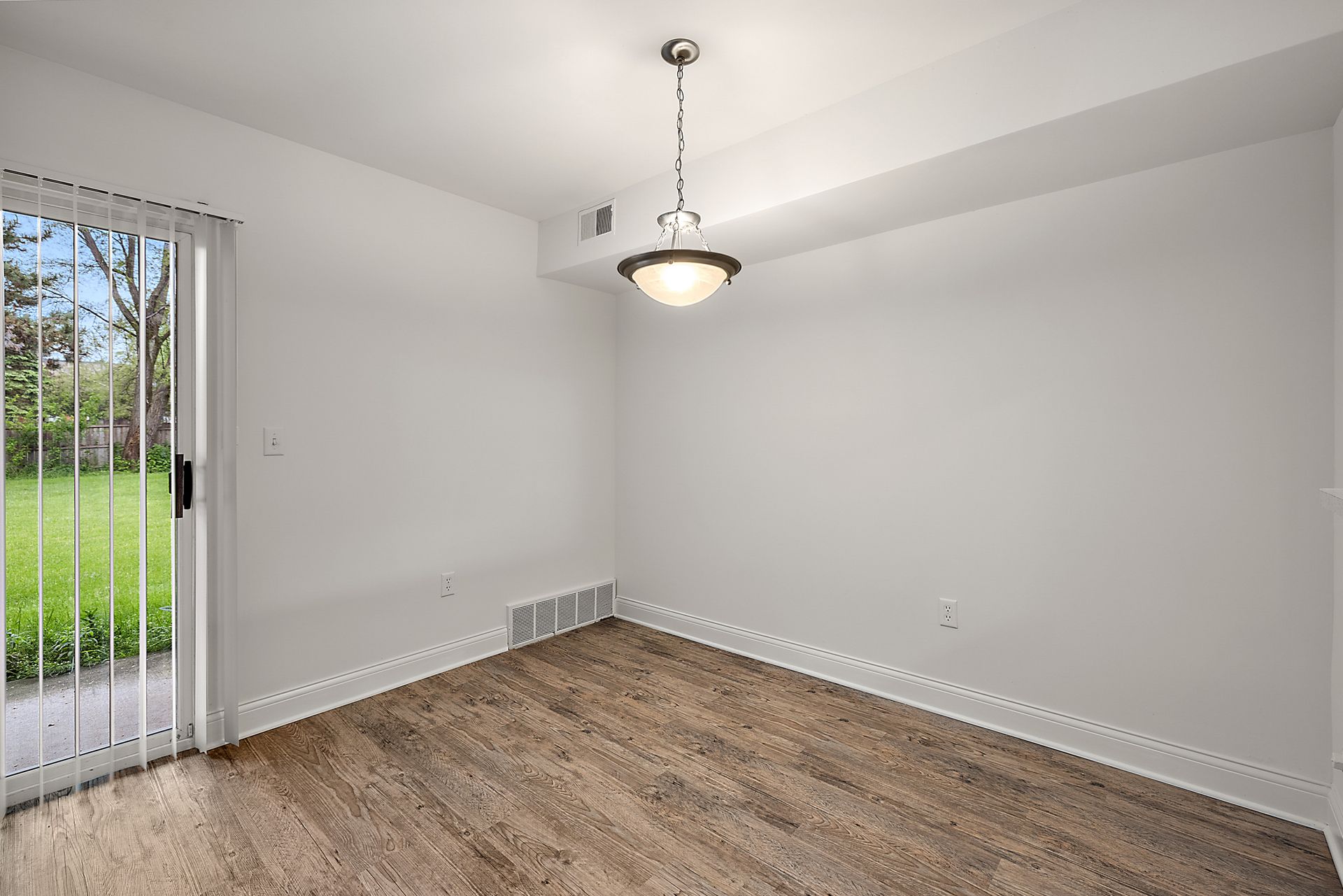 An empty room with a sliding glass door and a chandelier.