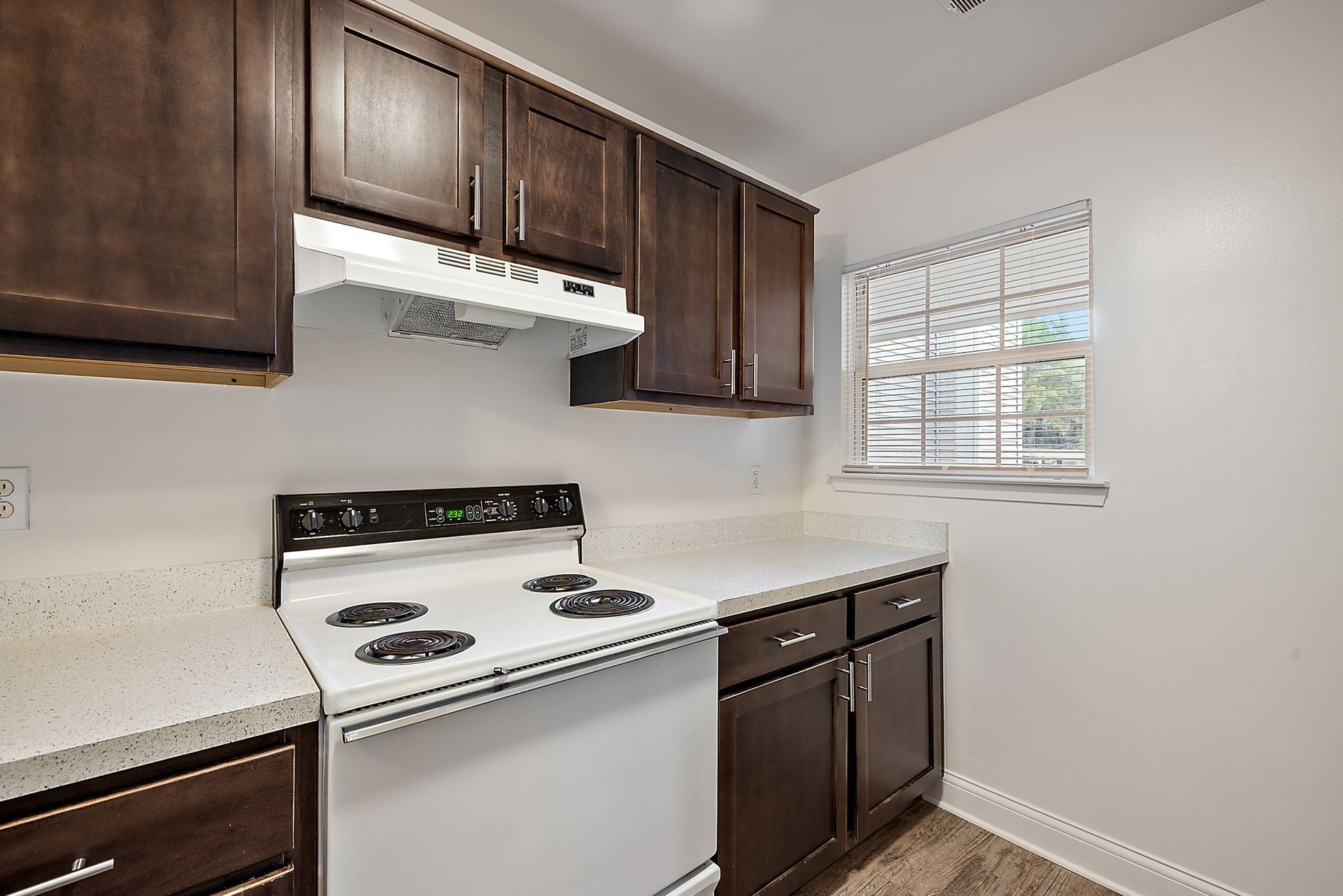 A kitchen with a stove , dishwasher , cabinets and a window.