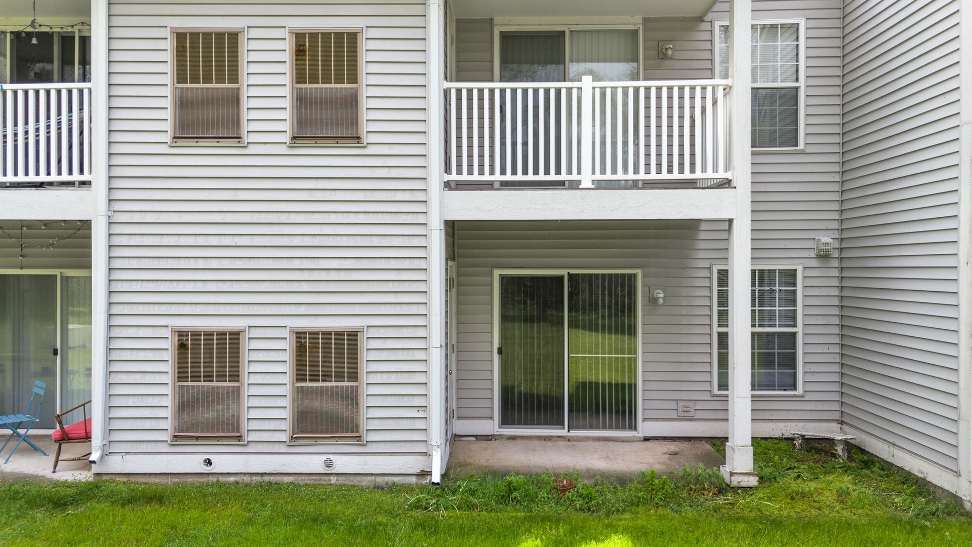 A white apartment building with a balcony and sliding glass doors.