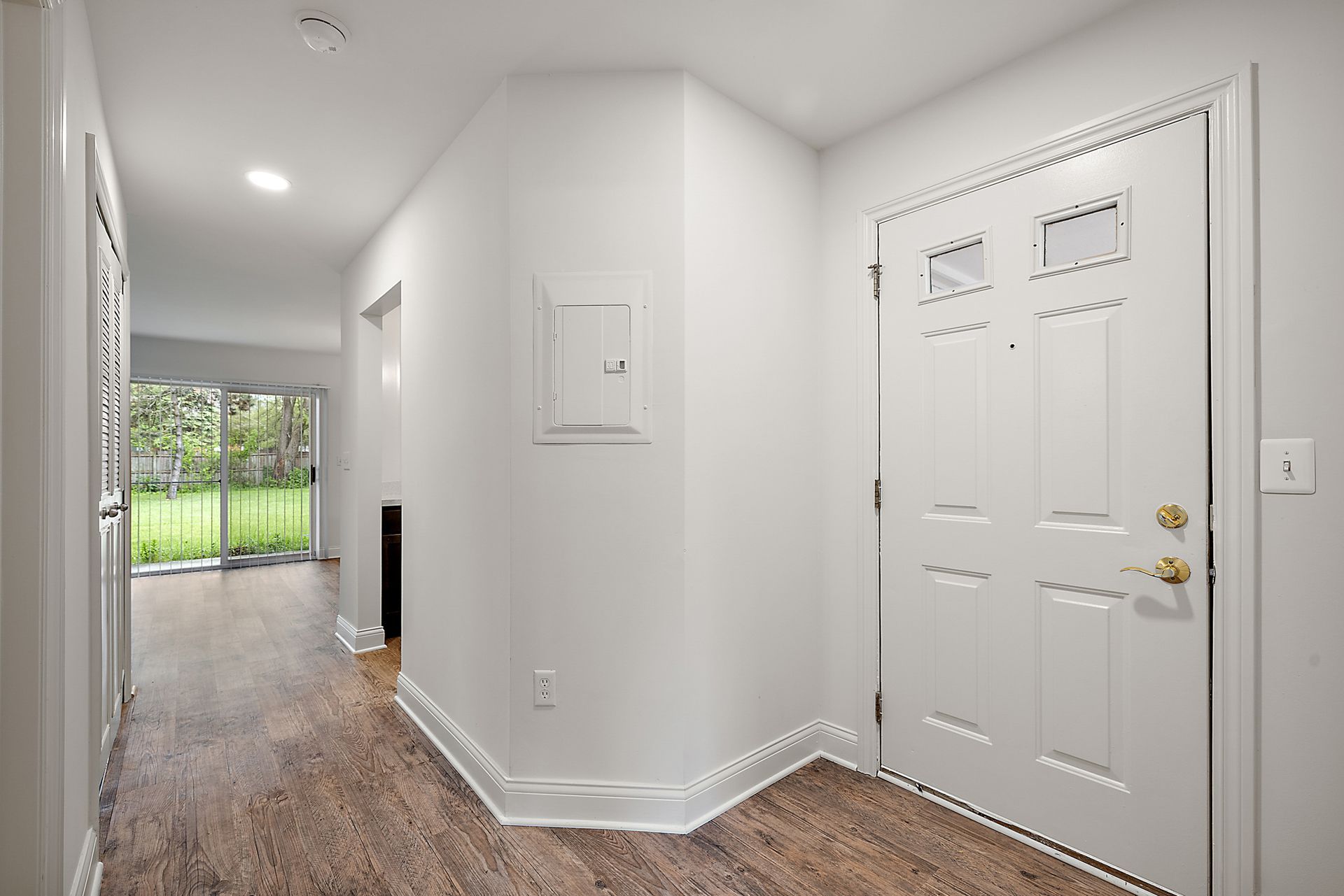 A hallway in a house with a white door and wooden floor.